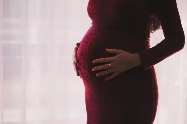 Schwangere Frau in einem engen roten Kleid in Seitenansicht